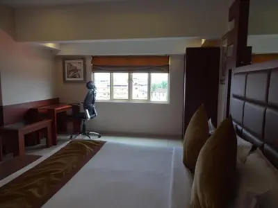 a bedroom with a bed and a desk and a window at Paramount Tower in Kozhikode