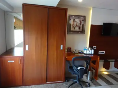 a wooden cabinet next to a desk with a chair at Paramount Tower in Kozhikode