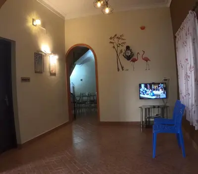 a living room with a blue chair and a tv at 7TH HEAVEN Kannur in Chakkarakkal