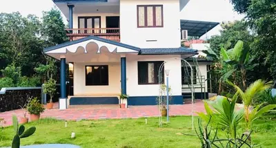 a large white house with a lawn in front of it at 7TH HEAVEN Kannur in Chakkarakkal