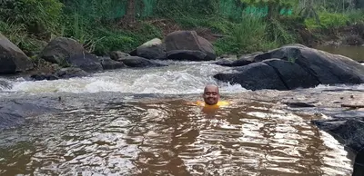 a man is swimming in a river at THE SUVISTARA WAYANAD KERALA in Meenangadi