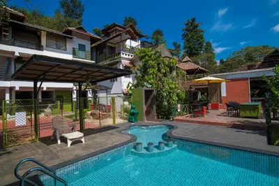 a swimming pool in front of a house at Olives The Boutique Resort in Kalpetta