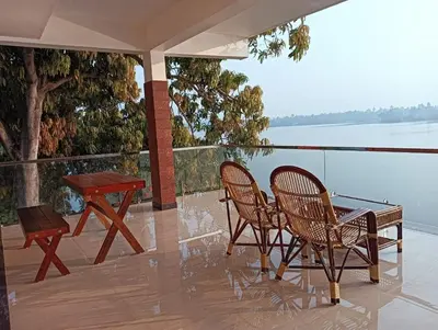 a patio with two chairs and a table with a view of the water at SAGAR BEACH VILLAS Home stay in Cherai Beach