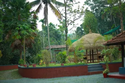 a resort with a building with a grass roof at Keloth Tharavadu in Panamaram