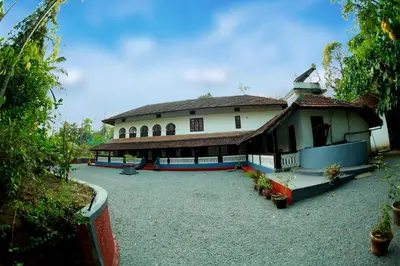 a large white house with a large courtyard at Keloth Tharavadu in Panamaram