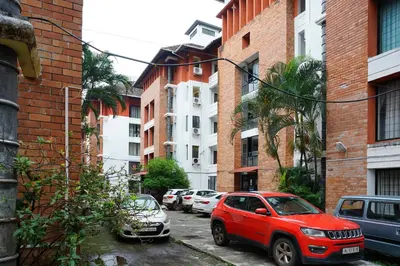 a red car parked on a city street with buildings at Vrindavan Suites Guruvayur in Guruvāyūr