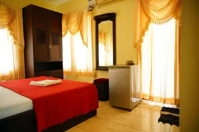a bedroom with a red blanket on a bed with windows at Vrindavan Suites Guruvayur in Guruvāyūr