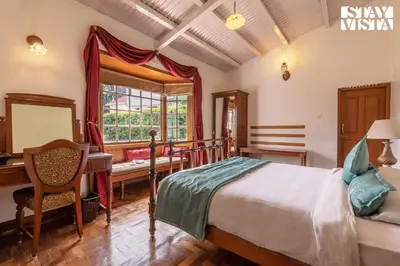 a bedroom with a bed and a desk and a window at Greenwood Bungalow Heritage In the heart of Ooty in Ooty