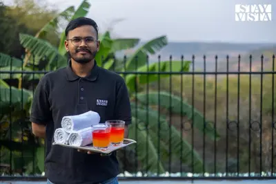 a man is holding a tray of drinks at Greenwood Bungalow Heritage In the heart of Ooty in Ooty