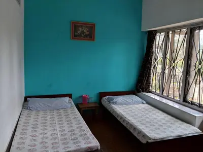 two beds in a room with blue walls and windows at REFLECTIONS Guest House in Ooty