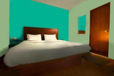 a bedroom with a large bed with a blue wall at REFLECTIONS Guest House in Ooty