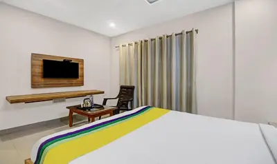 a bedroom with a bed and a desk and a tv at Itsy Hotels Vijaya Comforts, With Bar & Restaurant in Madikeri