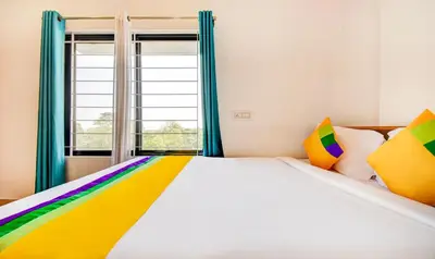 a bedroom with a rainbow bed with a window at Itsy Hotels Vijaya Comforts, With Bar & Restaurant in Madikeri