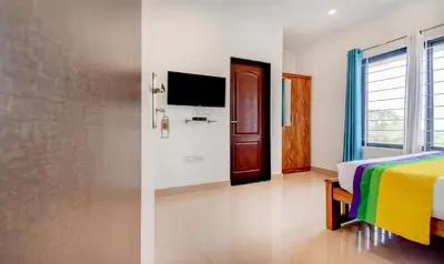 a hotel room with a bed and a tv at Itsy Hotels Vijaya Comforts, With Bar & Restaurant in Madikeri