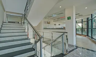 a staircase in a building with glass railing at Itsy Hotels Vijaya Comforts, With Bar & Restaurant in Madikeri