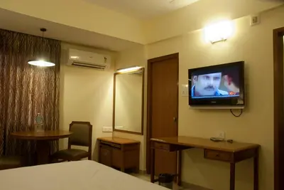 a hotel room with a bed and a television on the wall at Comfort Hotels in Coimbatore