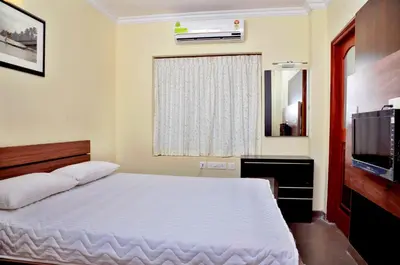 a bedroom with a white bed and a television at French Avenue in Kallāyi