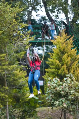 a woman is riding on a rope swing at Kadkani River Resort Coorg in Siddapur