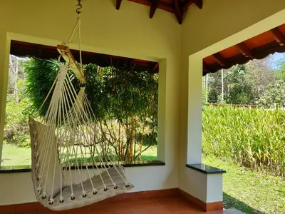 a porch with a hammock in front of a window at Kadkani River Resort Coorg in Siddapur