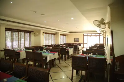 a dining room with tables and chairs and windows at Kallada Residency in Kodungallūr