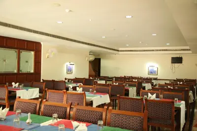 a dining room with tables and chairs and a tv at Kallada Residency in Kodungallūr