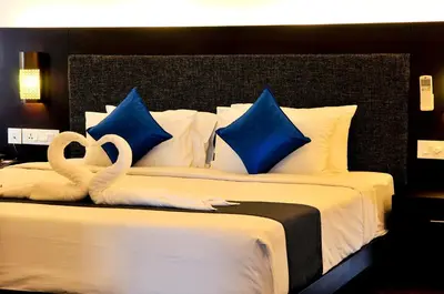 two swans sitting on a bed with blue pillows at Copper Folia in Kozhikode