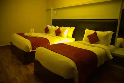 two beds sitting next to each other in a room at Hotel Wayanad Square in Mananthavady