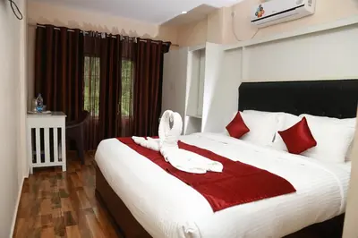 a bed with a white bird sitting on a red blanket at Hotel Wayanad Square in Mananthavady