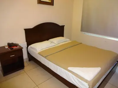 a small bedroom with a bed and a nightstand and a window at Hotel Sky Lite in Coimbatore
