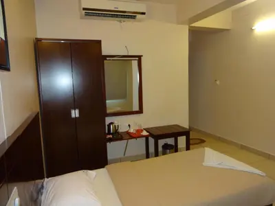 a bedroom with a bed and a cabinet and a table at Hotel Sky Lite in Coimbatore