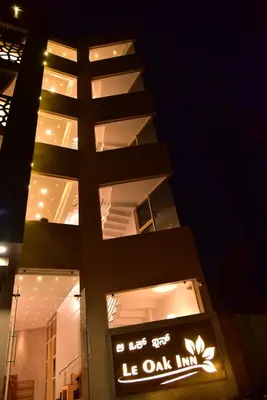 a building with a lit up sign in front of it at Le Oak Inn in Mysore