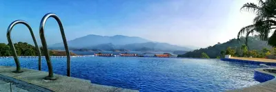 a large swimming pool with mountains in the background at CONTOUR ISLAND RESORT & SPA , wayanad in Tariyod