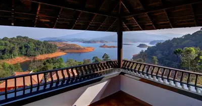 a balcony with a view of a river and mountains at CONTOUR ISLAND RESORT & SPA , wayanad in Tariyod