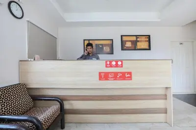 a man talking on a cell phone behind a counter at Super Hotel O Indra Comforts in Belagula