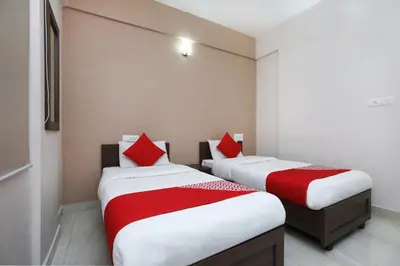 two beds in a small room with red pillows at Super Hotel O Indra Comforts in Belagula