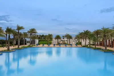 a large pool with palm trees and chairs at Le Meridien Coimbatore in Coimbatore