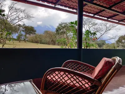 a wicker chair sitting on a porch with a table at Bamboo Banks Farm & Guest House in Masinagudi