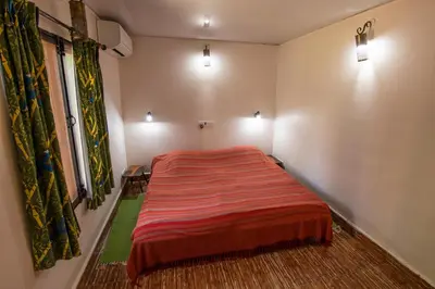 a bedroom with a bed with a red blanket at Bamboo Banks Farm & Guest House in Masinagudi