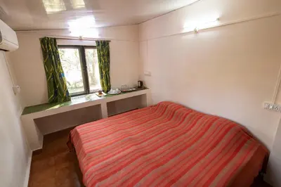a small bedroom with a bed and a window at Bamboo Banks Farm & Guest House in Masinagudi