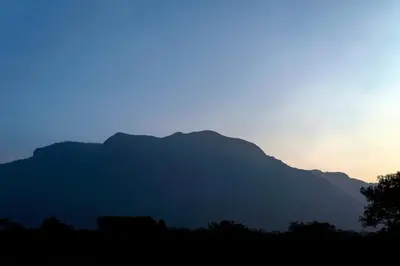 a silhouette of a mountain at sunset at Bamboo Banks Farm & Guest House in Masinagudi