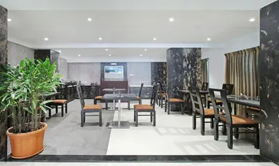 a restaurant with tables and chairs and plants at Itsy Hotels Jansi Residency in Coimbatore