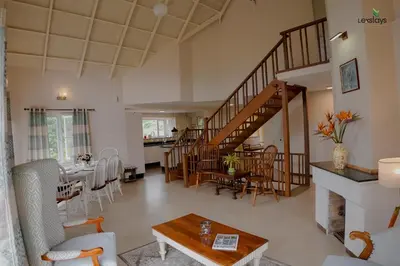 a living room with a staircase and a dining room at Yellow Tulip Hill Side Luxury Villa by LexStays in Coonoor