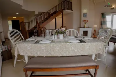 a dining room table with white chairs and a table cloth at Yellow Tulip Hill Side Luxury Villa by LexStays in Coonoor