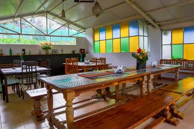 a room with tables and chairs and stained glass windows at Yellow Tulip Hill Side Luxury Villa by LexStays in Coonoor