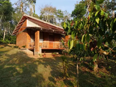 a brick house with a balcony in a forest at Estate Stay - Riverside Coffee in Siddapur