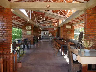 a restaurant with tables and chairs and a brick wall at Estate Stay - Riverside Coffee in Siddapur