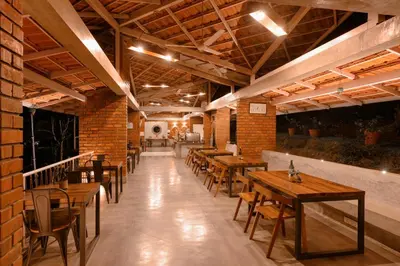 a restaurant with wooden tables and chairs and a brick wall at Estate Stay - Riverside Coffee in Siddapur
