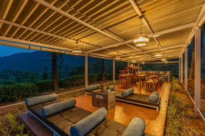 a patio with couches and a table and chairs at Zostel Plus Wayanad in Kalpetta