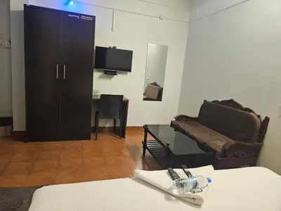a room with a black cabinet and a couch and a table at Apsara Residency in Perintalmanna