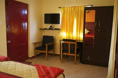 a room with a bedroom with a desk and a bed at The Bowers Chalet Private Campfire & Lawn BBQ, WIFI, Breakfast Hill Top 360 degree view in Ooty